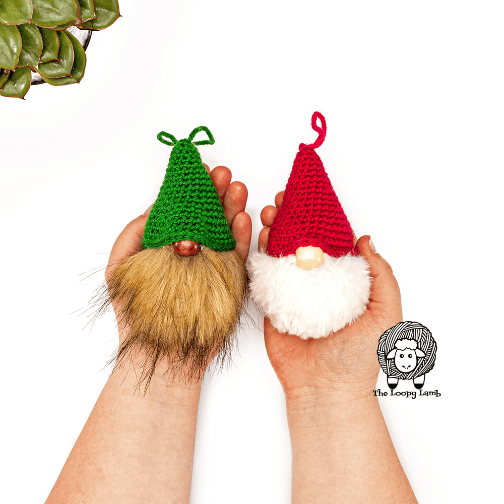 Hands holding two crochet gnome ornaments