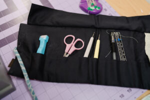 Girl holding handmade green gingham iPad sleeve sewn with Clover tools and pink flower button
