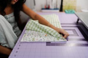 Girl holding handmade green gingham iPad sleeve sewn with Clover tools and pink flower button
