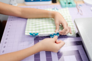 Girl holding handmade green gingham iPad sleeve sewn with Clover tools and pink flower button